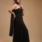 Woman in elegant black strapless gown posing against neutral beige background