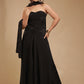 Woman in strapless black evening gown with scarf, gold bracelet, neutral backdrop