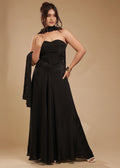 Woman in strapless black evening gown with scarf, gold bracelet, neutral backdrop