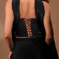 Woman in black satin lace-up back corset top and skirt, seen from behind