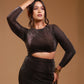 Woman modeling black shimmer cutout dress with long sleeves on a beige background