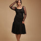 Woman wearing black mesh long sleeve dress with tulle skirt, posing on beige studio background